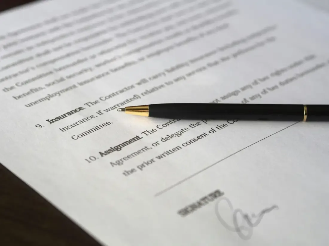Persona firmando un documento sobre un escritorio